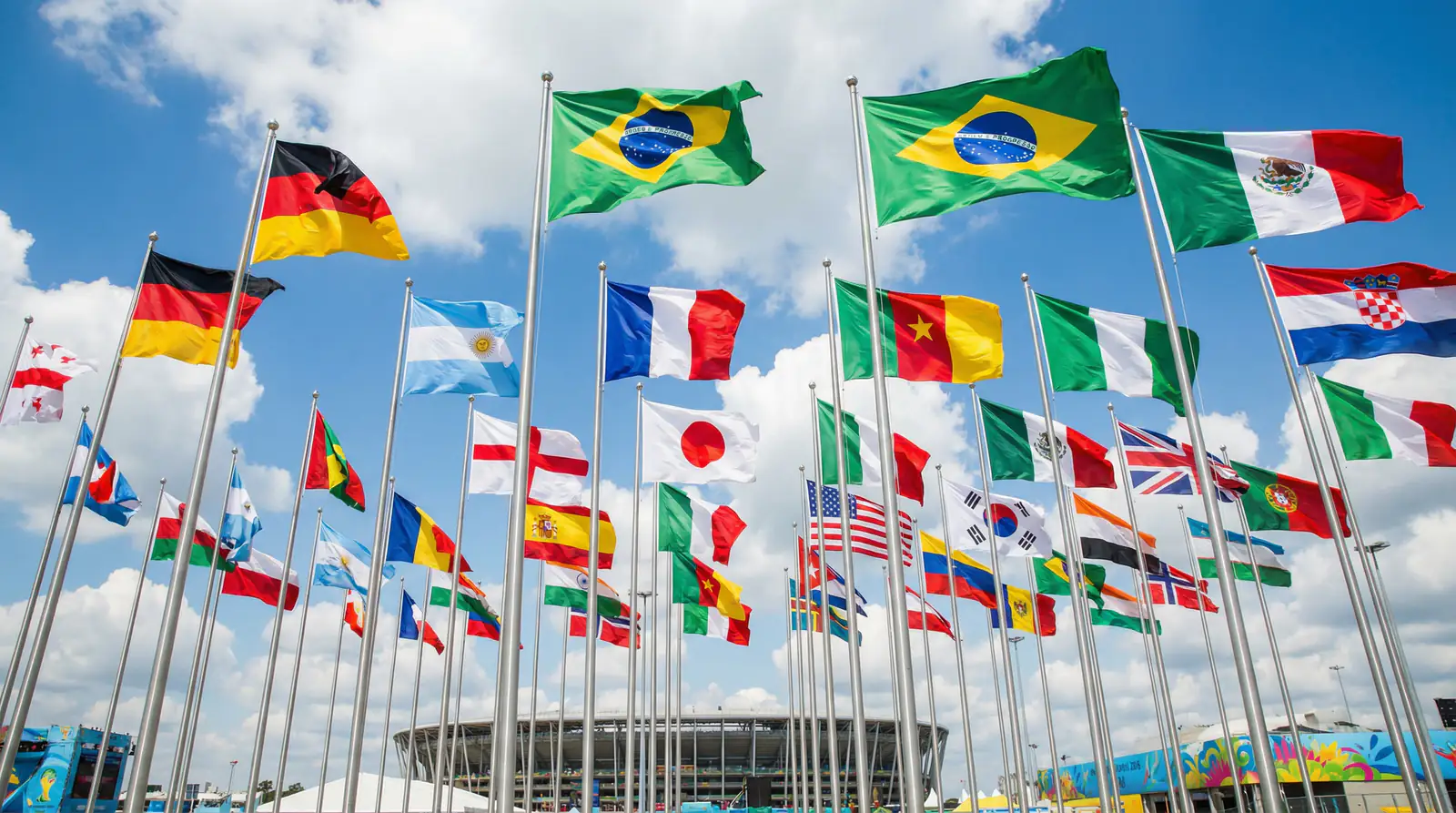 Verschiedene Nationalflaggen wehen im Wind vor blauem Himmel bei einem internationalen Fussballturnier
